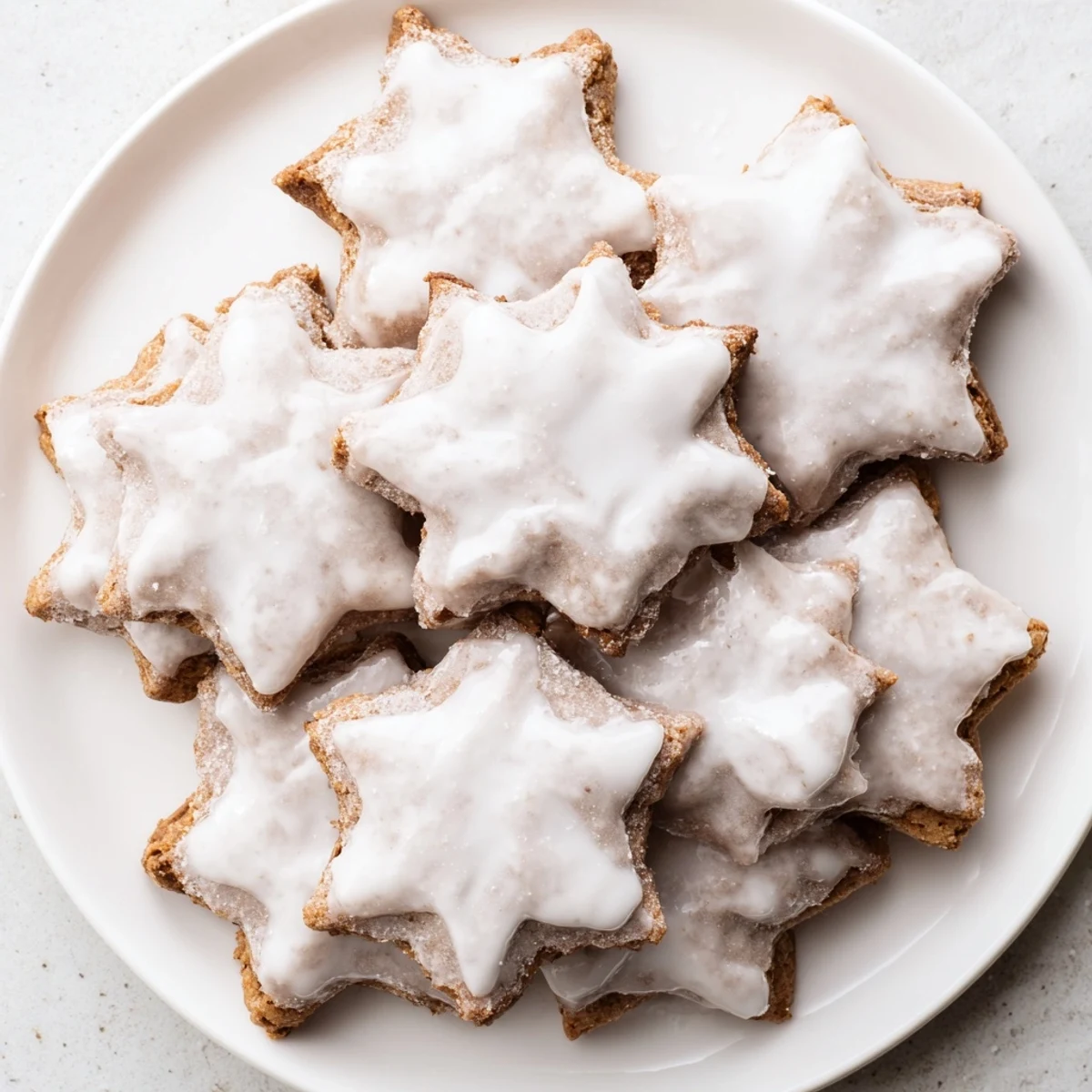 Golden, frosted Cinnamon Stars cookies on a festive plate, a delicious holiday treat.