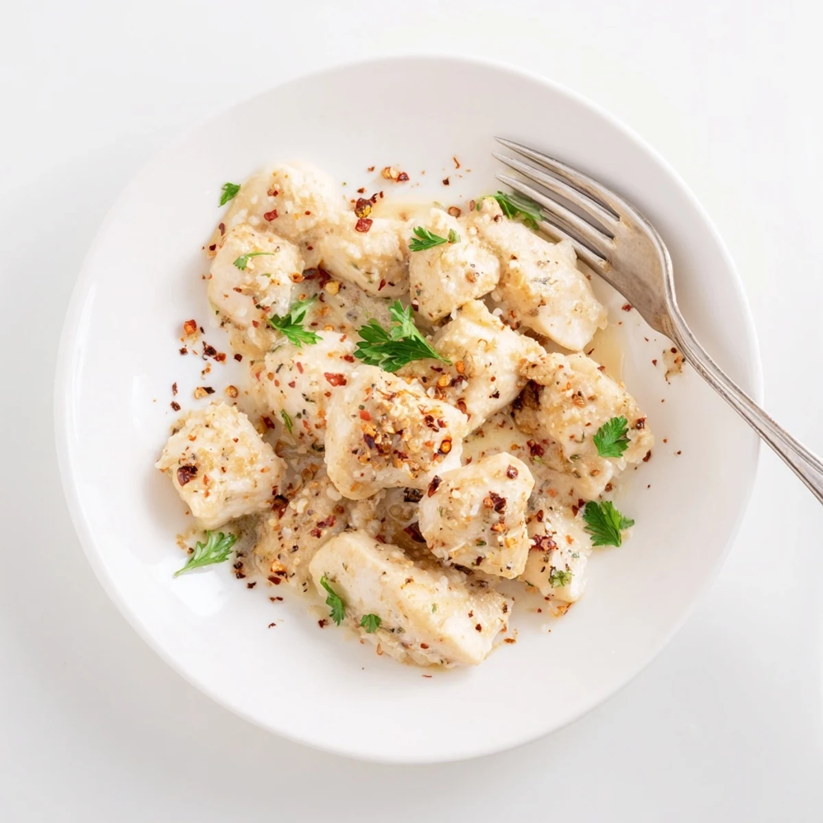 Tender, bite-sized chicken pieces simmered in a creamy garlic sauce, served over steamed rice for a comforting meal.