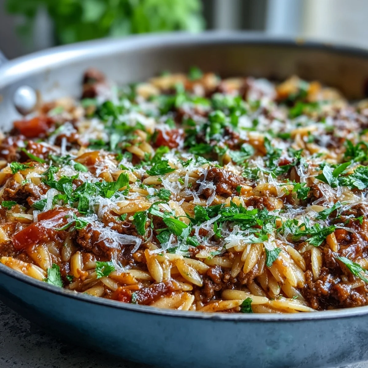 Frisch gekochtes Comforting Ground Beef Orzo Dinner mit roten Paprikastücken und erdigen Kräutern, dampfend auf dem Teller.
