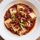 Close-up of bubbling Chinese Mapo Tofu: Silky tofu coated in spicy bean sauce ready to eat.