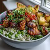 2. Herzhaftes Ananas-Teriyaki-Hähnchen auf lockerem Reis, garniert mit roter Paprika, Zuckerschoten und gerösteten Sesamkörnern.