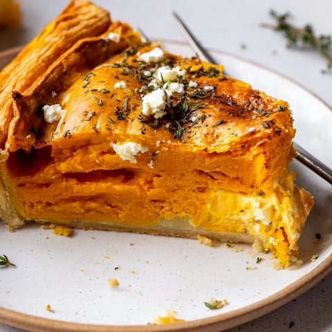 Cremige Savory Pumpkin Cheese Tart auf einem goldenen Teigboden mit herbstlichen Kräutern.