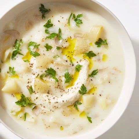 Creamy Garlic Potato Soup, a rich and comforting vegan dish with a swirl of fresh parsley and a drizzle of olive oil.