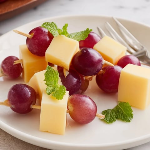 Käse- und Traubenspieße, abwechselnd mit Cheddar, Gouda und saftigen roten Trauben angerichtet.