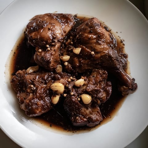 Tender Filipino Chicken Adobo, braised in a rich sauce, ready to serve with fluffy white rice.
