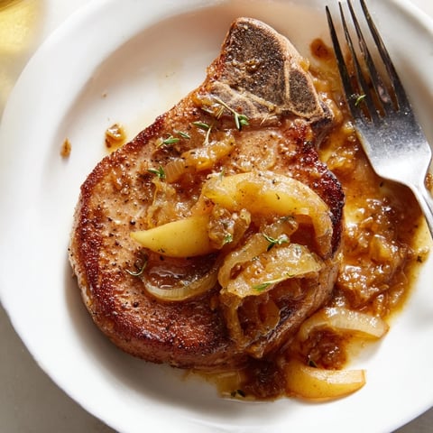 Saftige Schweinekoteletts mit fruchtiger Apfel-Senf-Sauce auf einem Teller serviert.  