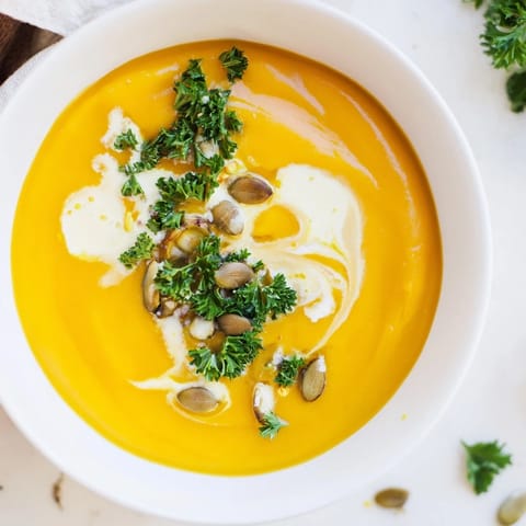 A bowl of warm pumpkin soup: smooth texture, with bread, perfect for a cozy fall meal.