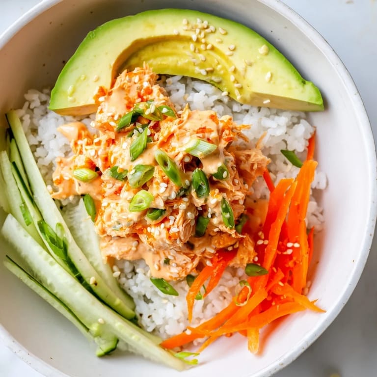 Flaky spicy canned salmon atop fluffy rice in this delicious rice bowl, served with fresh veggies.