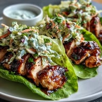 Saftiges BBQ-Hähnchenbrustfilet in knackigen Salatblättern, belegt mit knackigem, säuerlichem Krautsalat für eine gesunde, befriedigende Mahlzeit zum Abnehmen.