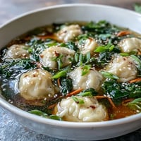 Schüssel mit asiatischer Dumpling-Suppe mit Bok Choy und Ingwer, mit zarten Dumplings und knackigem Bok Choy in aromatischer Brühe.